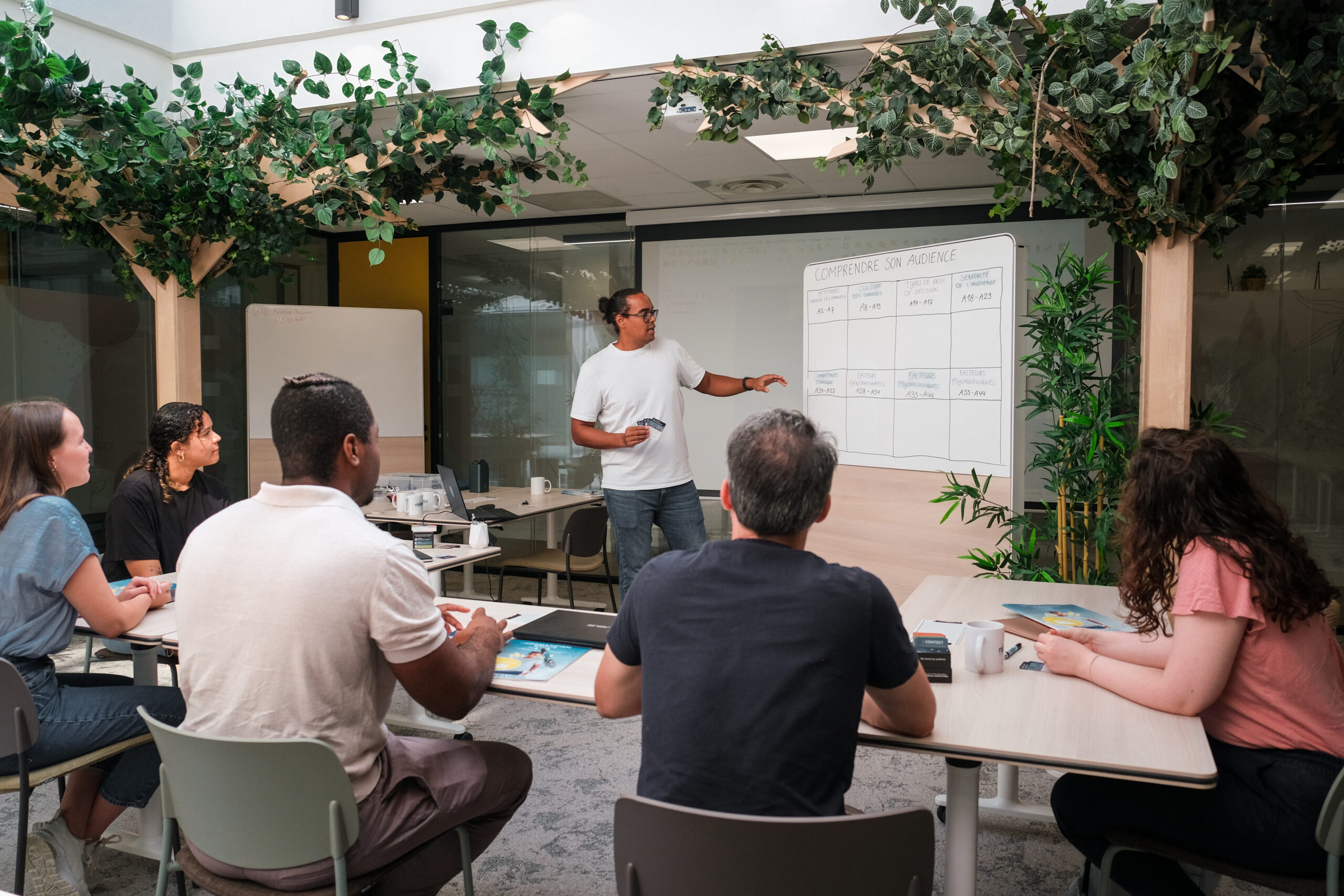 Emmanuel Ndofunsu anime une session de formation devant un groupe, face à un tableau de travail
